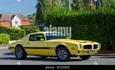 Bletchley, Bucks, UK - 25 agosto 2025: 1972 auto d'epoca gialla Pontiac Firebird americana che guida su una strada britannica Foto Stock