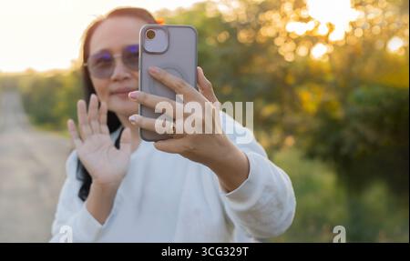 Donna asiatica adulta felice che scatta selfie o chiama vedio con il telefono con fotocamera mentre viaggia in vacanza. Foto Stock