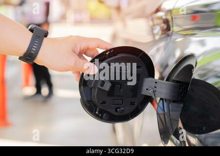 Close Up mans Hand aprendo un'auto nera con serbatoio. Aprire il coperchio della benzina della vettura. Concetto di rifornimento presso la stazione di servizio. Messa a fuoco selettiva. Foto Stock
