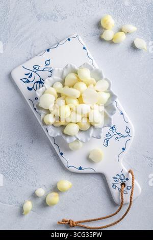 Cipolle piccole sottaceto in un recipiente sul tagliere Foto Stock