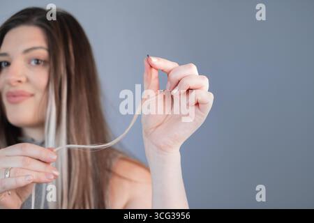 Bellezza e cura giovane donna con fili spessi dopo la procedura di estensione professionale dei capelli in un moderno salone di bellezza Foto Stock