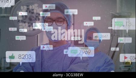 Chirurgo maschile e infermiere scrub che rivedono i monitor sotto la lampada chirurgica in SALA OPERATORIA, con icone sociali Foto Stock