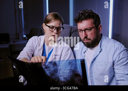 Medico donna caucasica che spiega la scansione medica a uomo caucasico di mezza età Foto Stock
