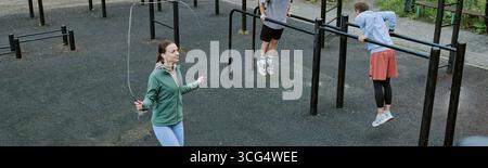 Fai un salto con la giovane donna caucasica che salta la corda mentre due uomini si allenano Foto Stock