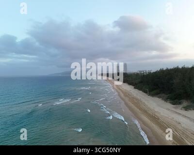 Vista aerea della costa di Sanya con oceano turchese, spiaggia di sabbia e lussureggiante foresta verde Foto Stock