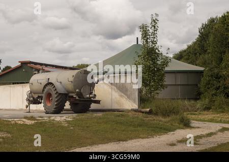 Rimorchio per autocisterna parcheggiato vicino allo stabilimento di biogas in un'azienda agricola in una giornata nuvolosa, concetto di agricoltura sostenibile Foto Stock
