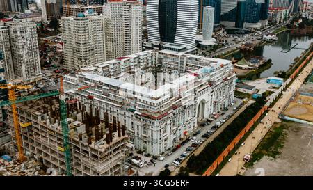 Gru che lavorano su un cantiere edile, edifici moderni e un lago sono visibili in questa vista aerea di batumi, georgia, una vivace città in rapido sviluppo Foto Stock