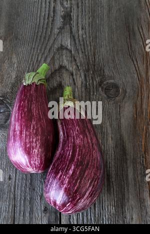 Melanzane fresche a strisce viola o melanzane isolate su fondo di legno. Cibo sano e vegetariano. Foto Stock