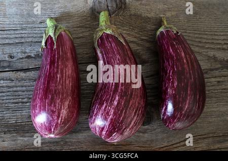 Melanzane fresche a strisce viola o melanzane isolate su fondo di legno. Cibo sano e vegetariano. Foto Stock