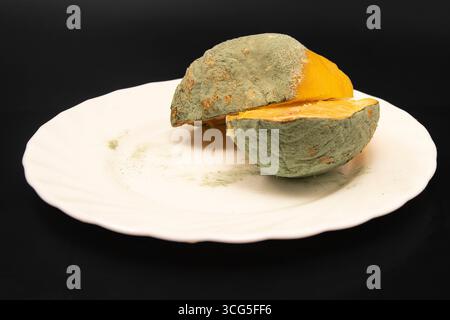 Primo piano di limone tagliato con muffa verde su piatto bianco concetto di spreco alimentare di agrumi rovinato e cibo malsano Foto Stock