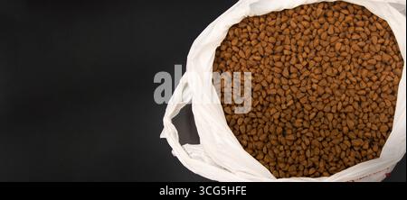 Primo piano di alimenti secchi per animali domestici in un sacchetto di plastica bianco isolato su sfondo nero concetto di cibo per gatti cibo per cani alimentazione animale e cura degli animali Foto Stock