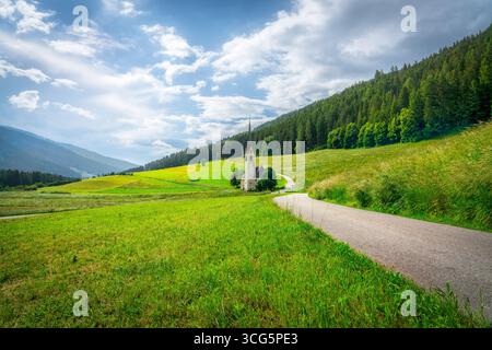 Pittoresca chiesa di Santa Maddalena di Villabassa incastonata nelle splendide Dolomiti, alto Adige. Paesaggio alpino mozzafiato con chiesa storica, g Foto Stock
