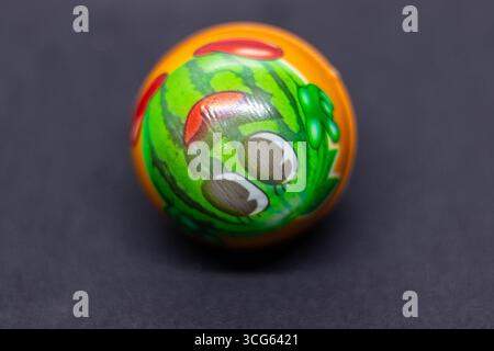 Palla giocattolo multicolore brillante per bambini appoggiati su un'elegante superficie nera, design vivace e giocoso, giocattolo colorato per bambini, oggetto isolato, divertimento, bambino Foto Stock