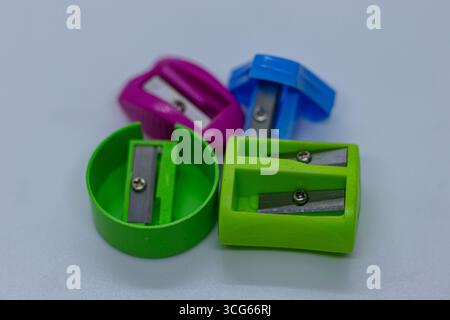 Affilatrice portatile compatta con lame in metallo affilate posizionate su un tavolo bianco liscio. Strumenti di cancelleria essenziali per la scuola, l'ufficio o l'arte. Foto Stock