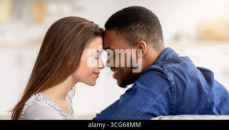 Momento romantico. Amorevole coppia interrazziale che si unisce a casa, primo piano Foto Stock