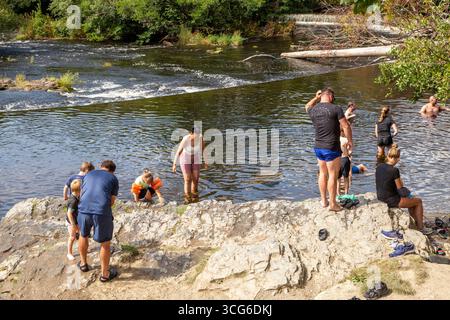 Persone che si godono il sole estivo delle onde di calore del 2025 sul fiume Dee alle Horseshoe Falls presso il resort di Llangollen nel Galles del Nord Foto Stock