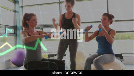 Guidare due donne che indossano abbigliamento sportivo sollevando manubri su palle da ginnastica in palestra, con palla viola Foto Stock