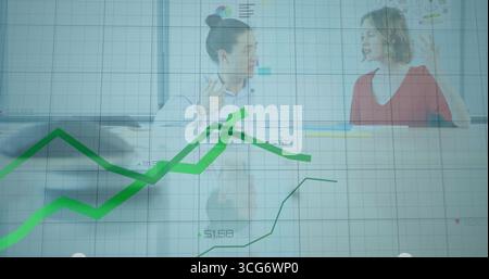 Discutere di donne d'affari che analizzano i grafici a linee su uno schermo di vetro con una penna per laptop al tavolo da conferenza Foto Stock