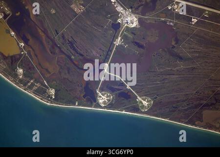 Lancia il complesso 39 al Kennedy Space Center, Merritt Island, Florida, Stati Uniti. Piattaforme di lancio, 39A e 39B.. Il Launch Complex 39 è stato utilizzato per molte missioni della NASA, tra cui i programmi Apollo e Space Shuttle. È ora utilizzato anche da società spaziali commerciali come SpaceX. Immagine tratta dalla stazione spaziale Internazionale. Le piattaforme di lancio sono circolari e circondate da canali. Questi canali vengono utilizzati per trasportare razzi e altre attrezzature alle piattaforme di lancio. Una versione ottimizzata di un'immagine ISS originale: Credit: NASA Foto Stock