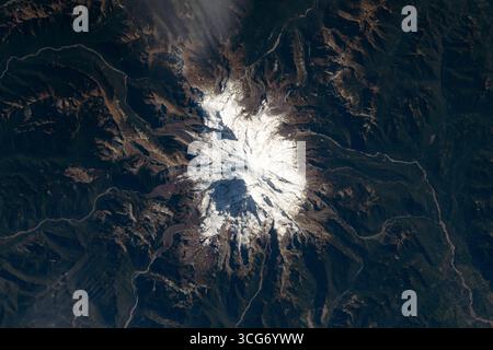 Il Monte Rainer, con il suo tetto ghiacciato, sale fino a 14.400 piedi (4.400 metri) sul livello del mare. Come la vetta più ghiacciata degli Stati Uniti contigui, il vulcano attivo degrada attraverso il Mount Rainer National Park, a sud-est di Seattle. La stazione spaziale Internazionale ha orbitato 260 miglia sopra il Pacifico nord-occidentale mentre questa fotografia è stata scattata. Una versione ottimizzata di un'immagine ISS originale: Credito: NASA/ESA. Solo per uso editoriale. Foto Stock
