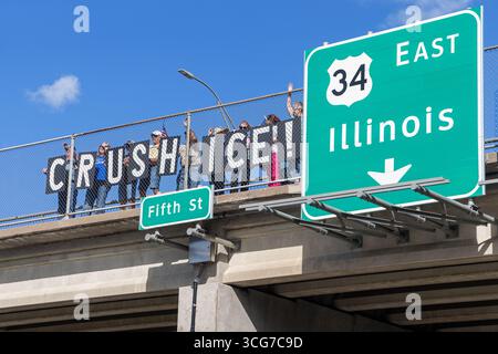 Burlington, Iowa, Stati Uniti. 26 agosto 2025. Gli attivisti politici del gruppo indivisibile dell'Iowa hanno tenuto segnali di "SCHIACCIAMENTO DEL GHIACCIO" su un cavalcavia autostradale per protestare contro la politica di applicazione dell'immigrazione degli Stati Uniti. Credito: Keith Turrill/Alamy Live News Foto Stock