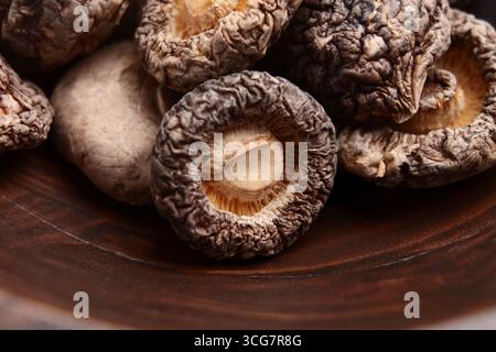 Funghi shiitake crudi disidratati in una ciotola rustica in legno. Cibi secchi Foto Stock