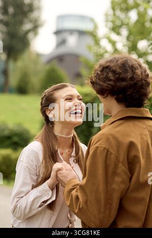 Una giovane coppia gioiosa condivide una piacevole passeggiata nel parco, avvolta da amore e risate. Foto Stock