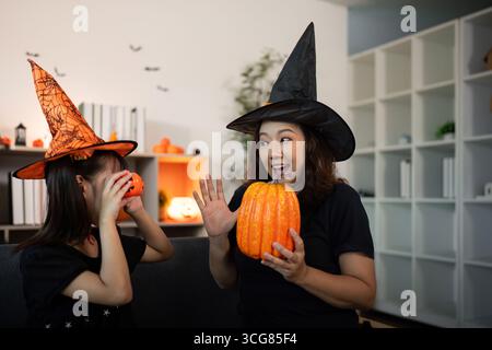 Festa di Halloween. Mamma e figlia si godono momenti festivi con zucche e cappelli da streghe. Foto Stock