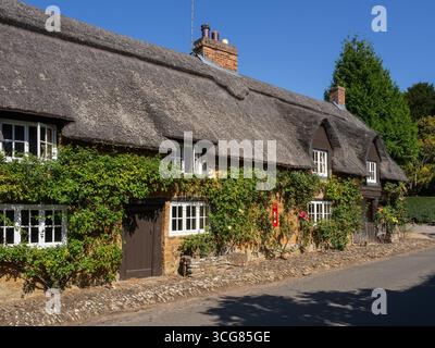 Fila di cottage terrazzati con tetto di paglia nella pittoresca frazione di Brockhall, Northamptonshire, Regno Unito Foto Stock