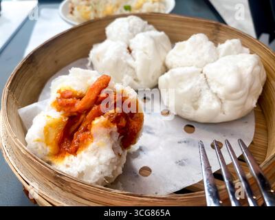 Panini cotti al vapore ripieni di maiale in un cestello per vaporiera Foto Stock