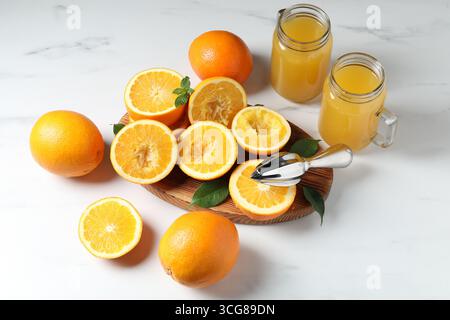 Succo d'arancia appena spremuto, frutta e centrifuga sul tavolo bianco Foto Stock