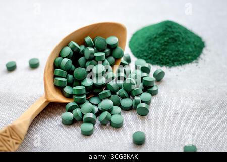 Spirulina di alghe verdi in compresse e polvere su sfondo di burlap. Proteine vegetali Foto Stock