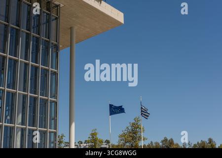Veduta dell'architettura angolare della Fondazione Stavros Niarchos accostata a un cielo azzurro luminoso con bandiere che sventolano dolcemente, Athina, Attica, Gree Foto Stock