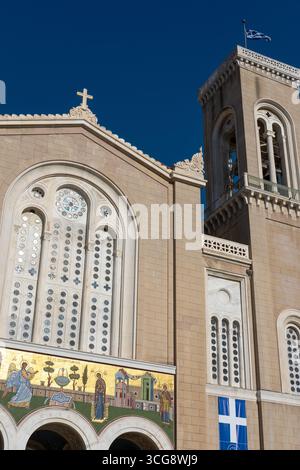 La vista della Cattedrale metropolitana di Atene si erge alta, con la sua pietra beige che contrasta con il vibrante cielo blu, una croce sulla sua struttura, Atene Foto Stock