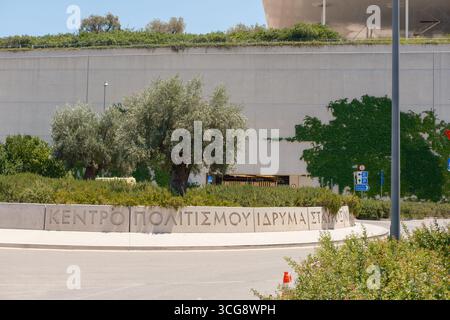 La vista degli ulivi si erge orgogliosamente contro le austere pareti di cemento e la vegetazione lussureggiante, con texture contrastanti ad Athina, Attica, Grecia. Foto Stock