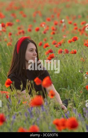 Giovane donna in Poppy Field con ritratto Red Hat Foto Stock