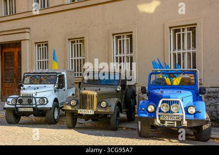 uzhhorod, ucraina - 31 ottobre 2021: tre veicoli fuori strada pronti per l'uso. auto con bandiere ucraine su una strada asfaltata. il vecchio trasporto militare ha modificato l'an Foto Stock