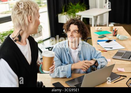 Due giovani interagiscono in un ufficio contemporaneo, condividendo idee e godendosi la giornata lavorativa. Foto Stock