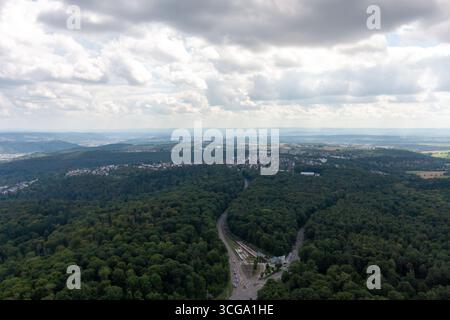 Vista aerea di una lussureggiante foresta verde con una strada tortuosa che attraversa, confinante con un'area residenziale della città di Stoccarda. La scena cattura l'intervallo Foto Stock