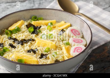 Zuppa di saimin hawaiana con teneri tagliatelle all'uovo, alghe, cipolle verdi, omelette e kamaboko giapponese da vicino in un piatto sul tavolo. orizzontale Foto Stock