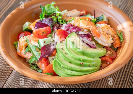 Vivace insalata di gamberi avocado verdure fresche condimento agrumi tavolo in legno rustico Foto Stock