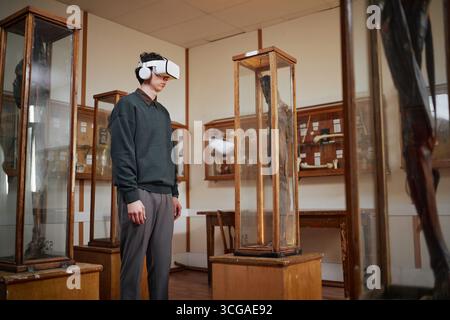 Giovane uomo caucasico adulto che utilizza le cuffie per realtà virtuale in esposizione scientifica Foto Stock