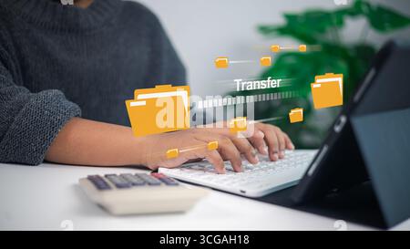 Uomo d'affari che digita sulla tastiera con icone di cartelle digitali, trasferimento di file online, archiviazione su cloud e tecnologia di condivisione dei dati per comunicazioni sicure e Foto Stock