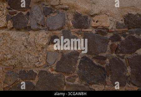 Vecchio muro in muratura in pietra vulcanica e mattoni, sfondo rustico per progetti di design Foto Stock
