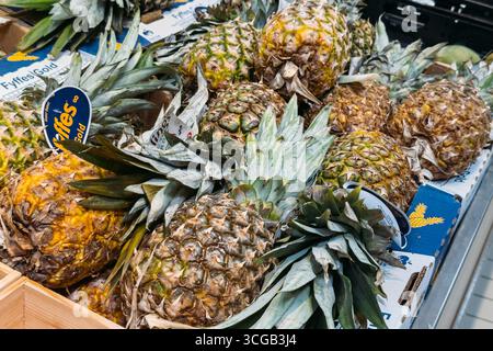 Ananas freschi impilati alla rinfusa in un negozio di alimentari. Lione, Francia - 19 agosto 2025 Foto Stock