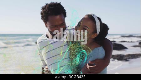 Coppia sorridente che indossa un top a spalla e una t-shirt bianca che abbraccia la spiaggia con l'archetto bianco Foto Stock