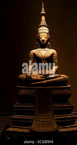 Una statua splendidamente realizzata di una figura seduta con dettagli intricati, illuminata su uno sfondo scuro Foto Stock