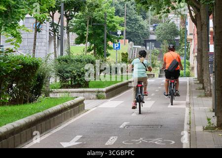 Coppie anziane che si godono una piacevole corsa sulle loro biciclette elettriche lungo una pista ciclabile dedicata, promuovendo uno stile di vita sano e sostenibile Foto Stock