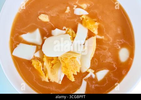 Primo piano di una ciotola di salmorejo rinfrescante, una tradizionale zuppa fredda spagnola, condita con uova sode tritate Foto Stock