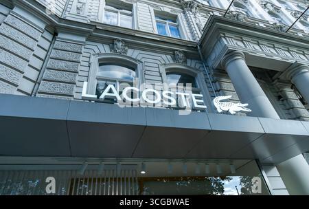 Vista grandangolare del logo di coccodrillo Lacoste e delle scritte del marchio su una facciata storica lungo Kurfürstendamm a Berlino. Foto Stock